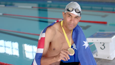 proud swimmer displays his gold medal at the pool with the australian flag