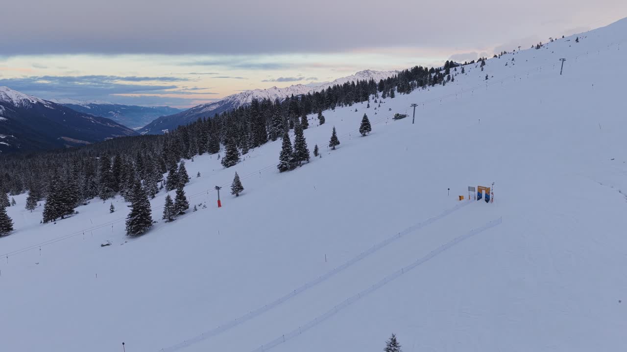 Vista aerea di gatti delle nevi che preparano piste da sci lisce nella Zillertal Arena, a Krimml e Königsleiten, Austria, con montagne innevate.