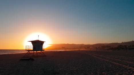 Toma-Panorámica-De-La-Puesta-De-Sol-De-La-Playa-Estatal-De-San-Buenaventura-Con-Casa-De-Salvavidas:-Torre-En-Ventura,-California,-Estados-Unidos