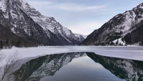 Aerial winter view of frozen Klöntalersee lake reflecting Swiss Alps in Klöntal, Switzerland