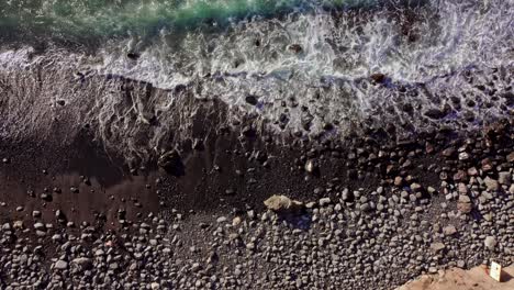 4k aerial top down shot of rocky beach waves at coast in tenerife