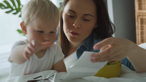 Woman-and-her-little-son-browsing-pregnant-photographies-on-bed.