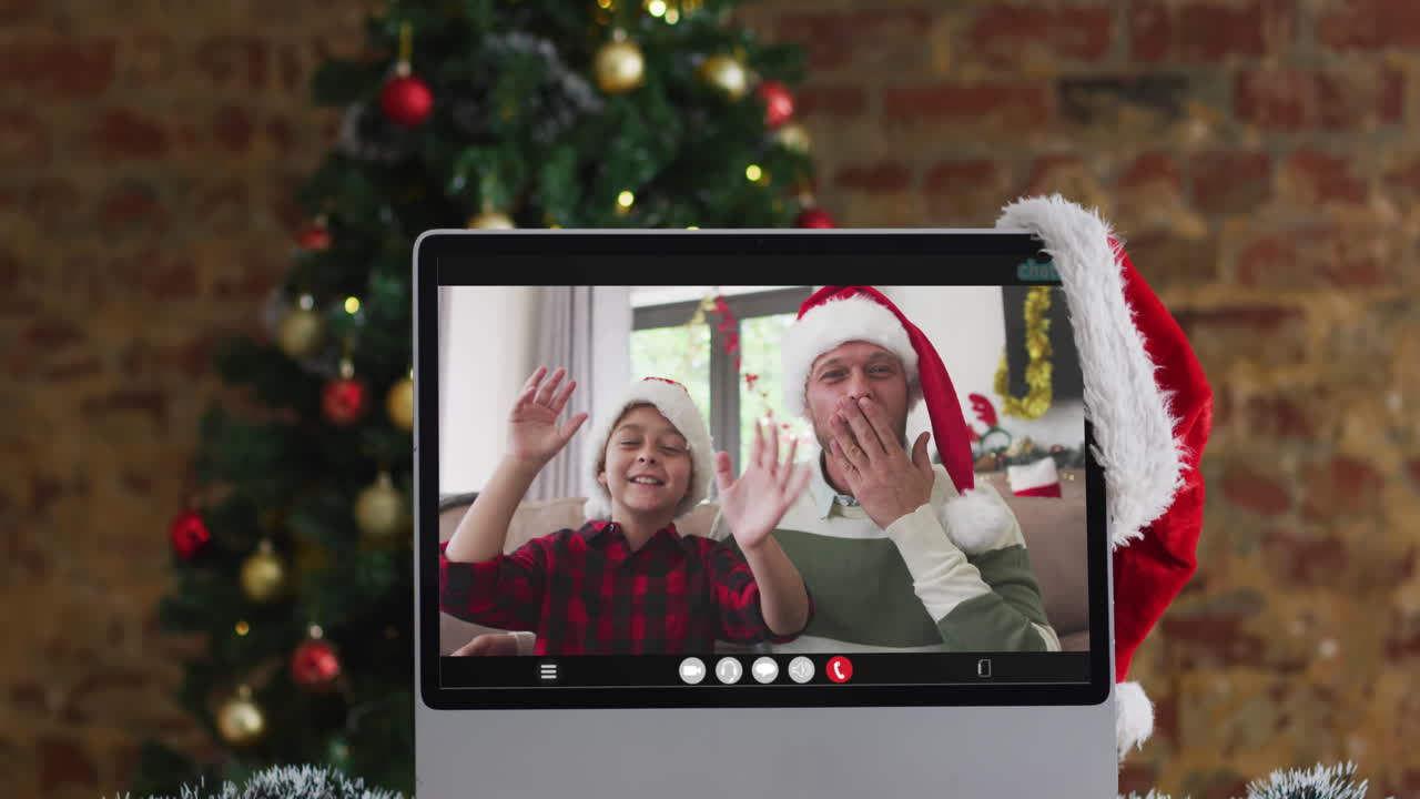padre y hijo felices saludando en una videollamada en la computadora, con decoraciones de navidad y árbol