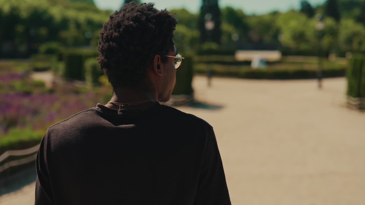 Young African American Man Puts on Sunglasses in a Sunny Park