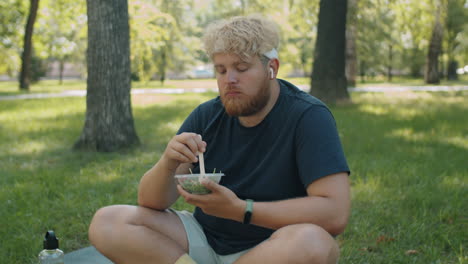 overweight man eating salad in park