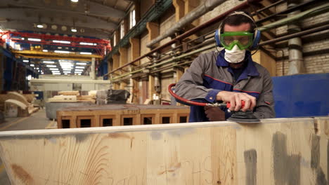 trabajador lijando tablas de madera en una fábrica