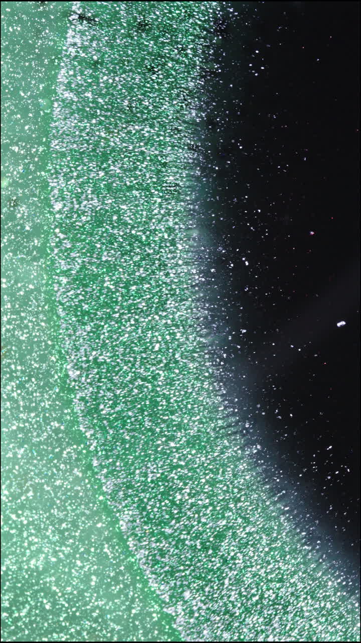 Macro shot of liquids mixing with a sparkling effect, vertical view