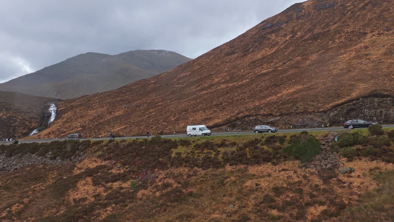 Cars driving on mountain road near waterfall in scotland