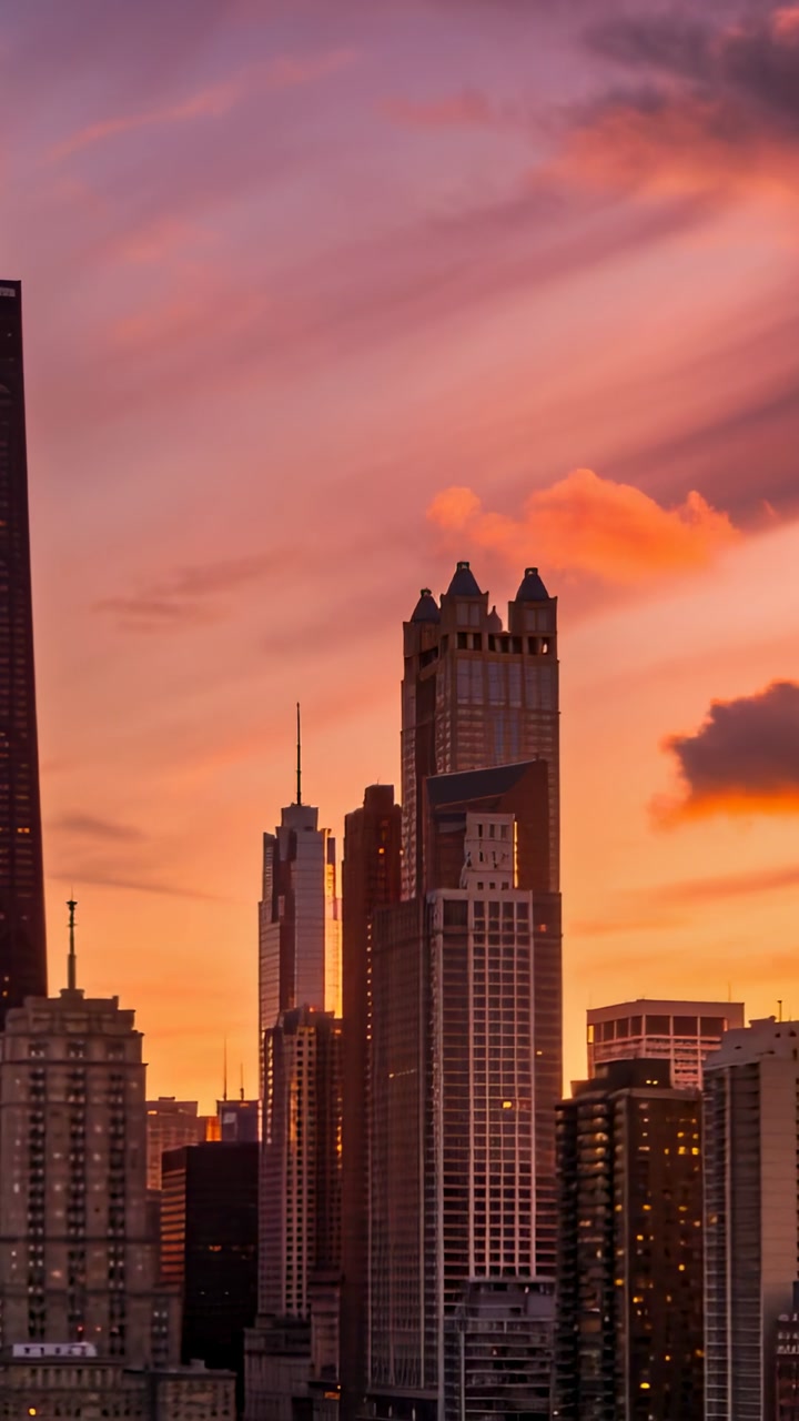 Vertical video: Panning cam filming towers with sky deepening at sunset to capture skyline spires