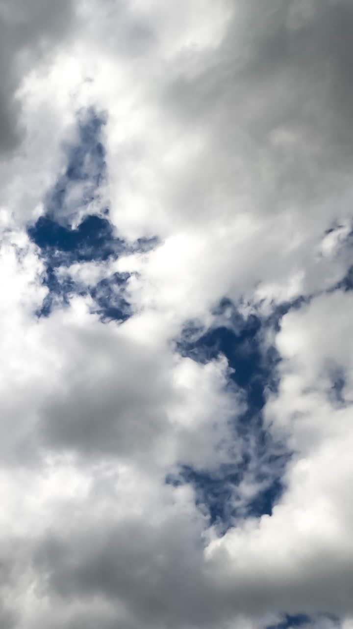 Grey clouds covering the blue sky totally. Bright sun breaking through the cloudscape. Timelapse. Vertical video