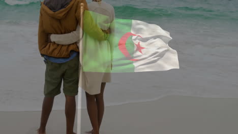 embracing on beach, couple with algerian flag waving in background