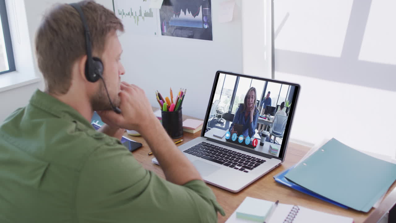 Kaukasisk mand bruger bærbar computer og telefonheadset på videoopkald med en kvindelig kollega.