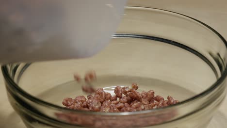 pouring cereal into a glass bowl