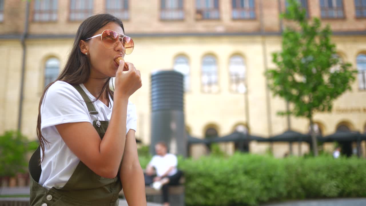Giovane donna che mangia un gelato in città