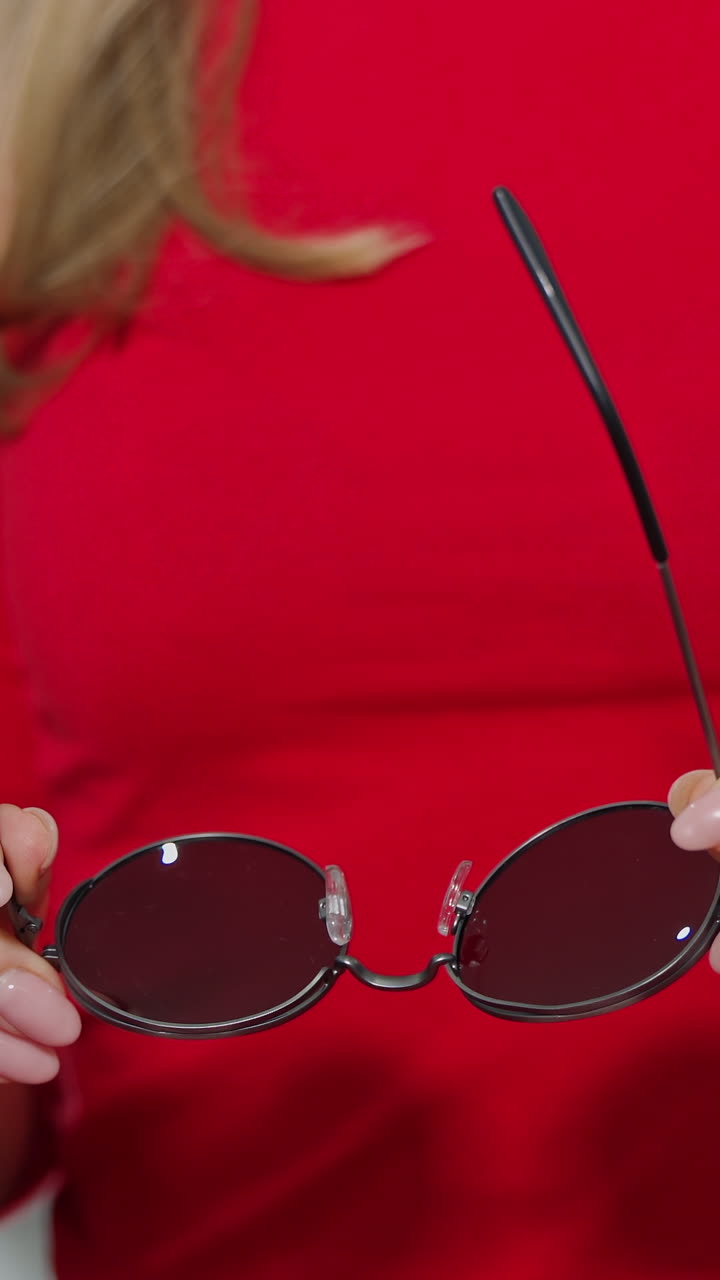 Cute girl with new glasses in shop. Young woman choosing sunglasses in store