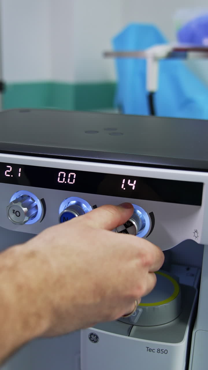 Doctor's hand turning the handles on the anesthesia delivery system. Anesthesiologist's preparation for the surgical operation in modern clinics. Vertical video