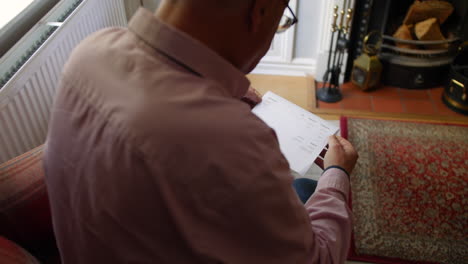 a lonely senior man opening a debt letter