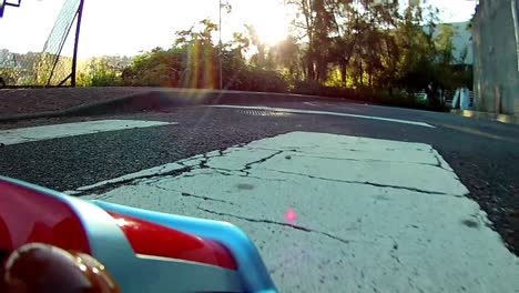 rc radio control toy car racing on a real asphalt track with sun rays shinning through the natural trees on the sidewalk