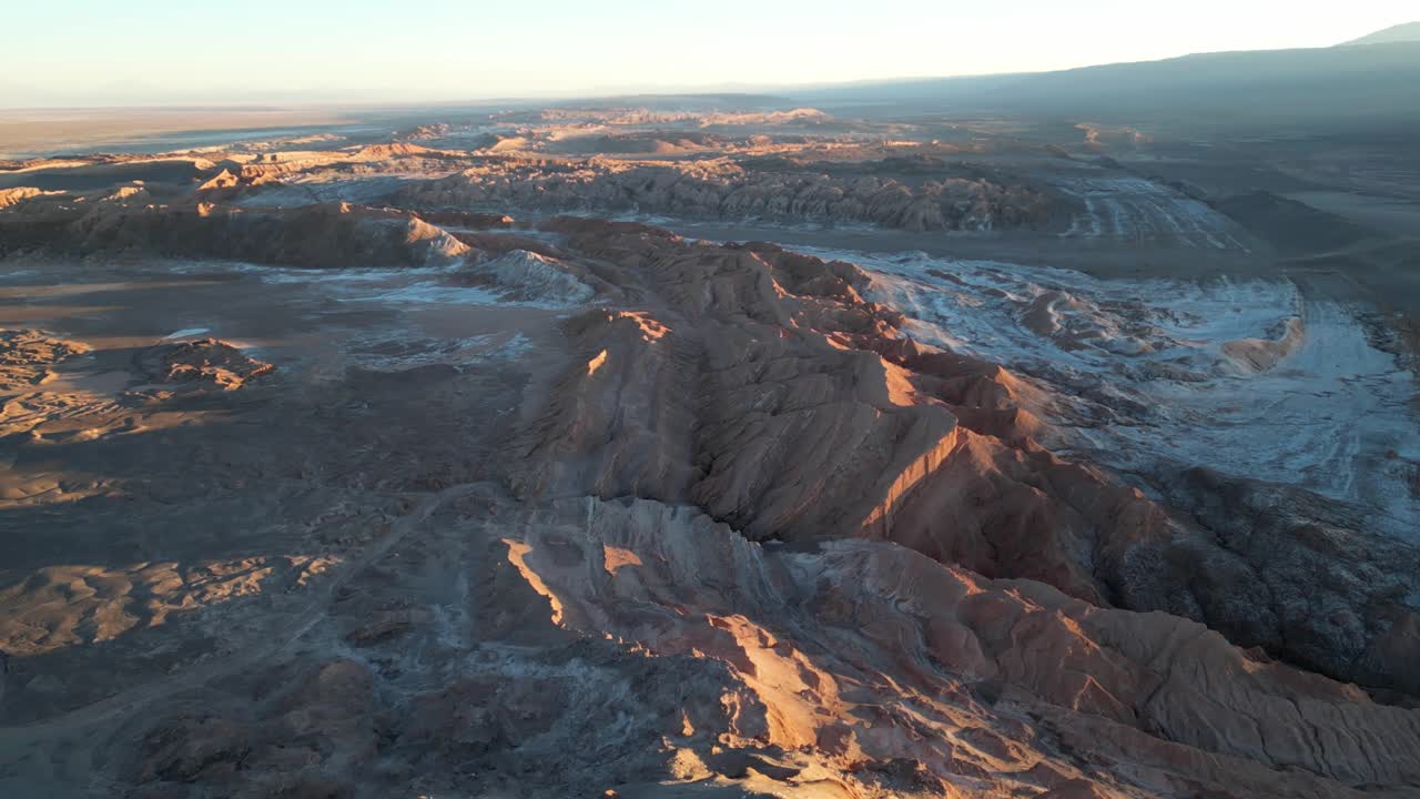 High-resolution aerial view of rugged desert terrain and white salt flats glowing at dusk in Chile’s Valley of the Moon