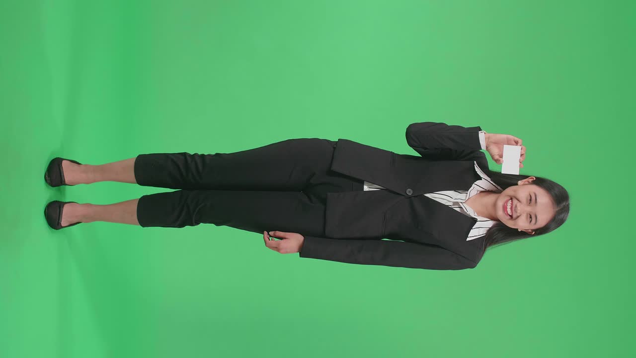 Full Body Of An Asian Business Woman With Smile Holding A White Card While Standing In Front Of Green Screen