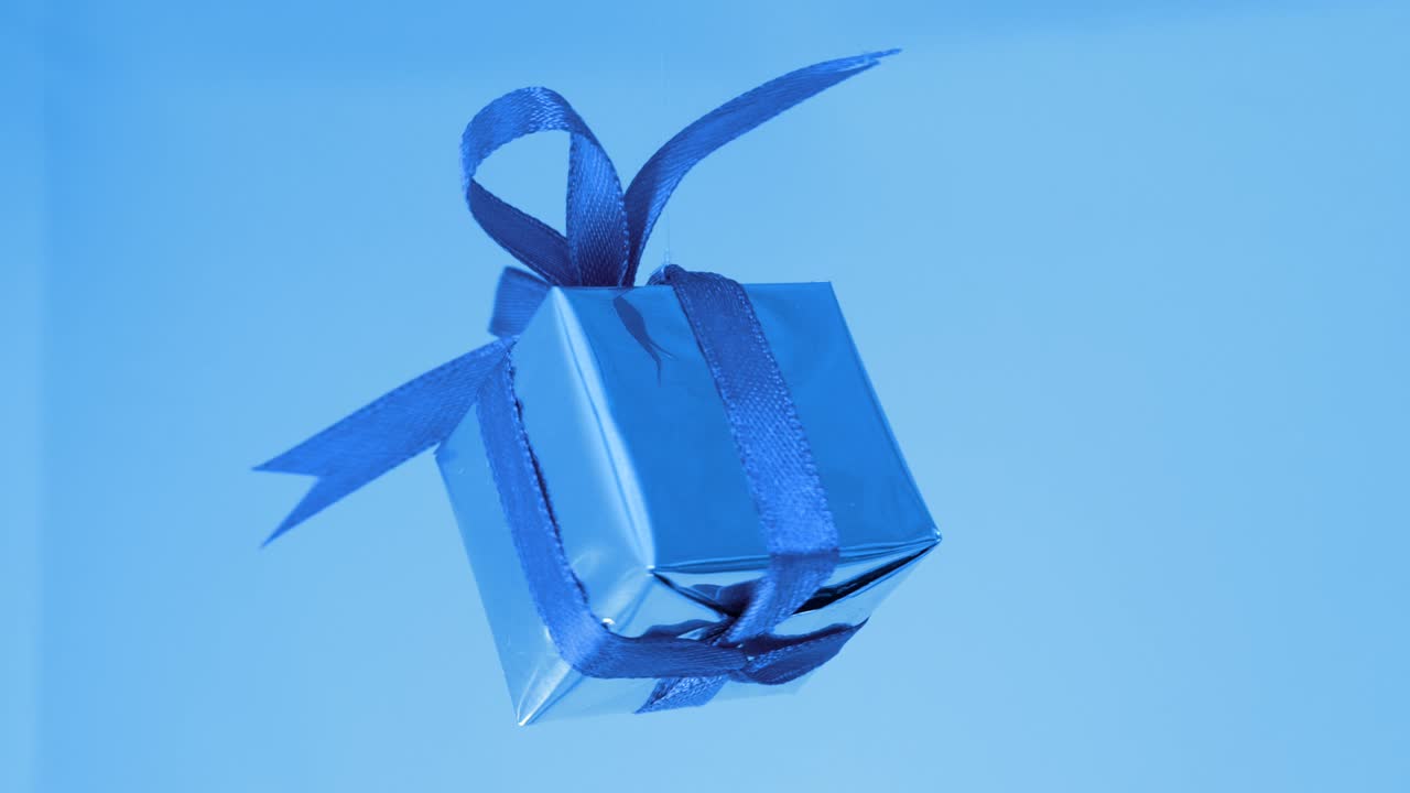 caja de regalos con cinta azul girando sobre fondo azul. rotación de 360 grados