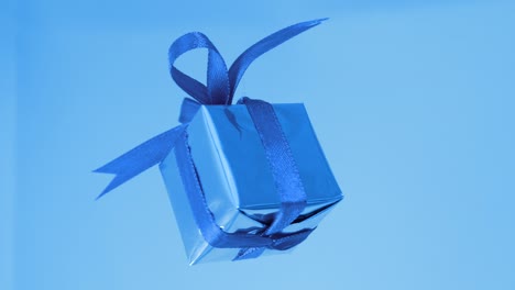 gift box with blue ribbon spinning on blue background. 360 degree rotatio