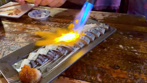 sushi being flambéed with a blowtorch