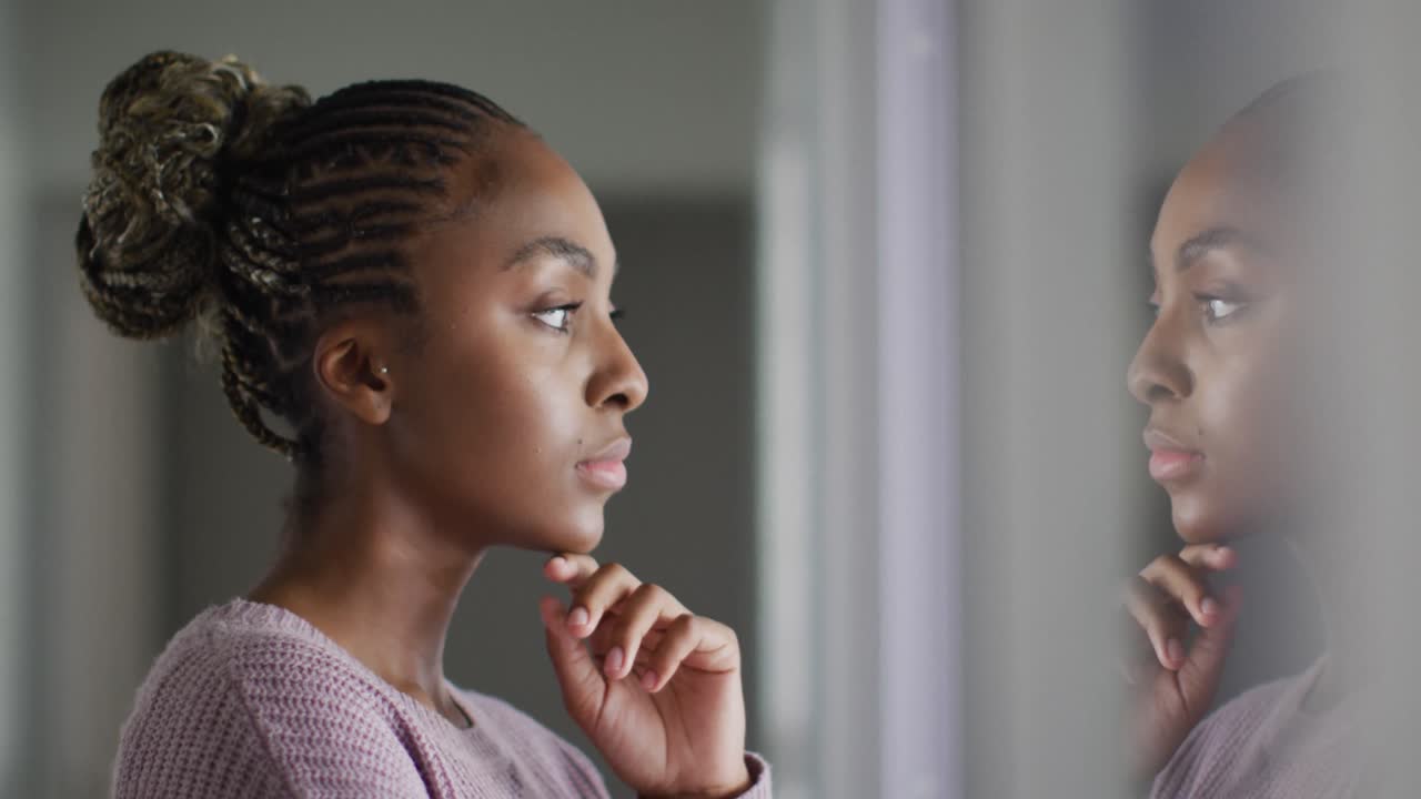 Thoughtful african american woman looking outside window