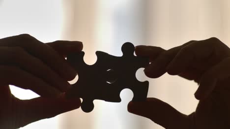 close up hands of woman connecting jigsaw puzzle with sunlight affect. business solutions, success strategy. two hands connect couple puzzle. one part of whole symbol of association and connection.