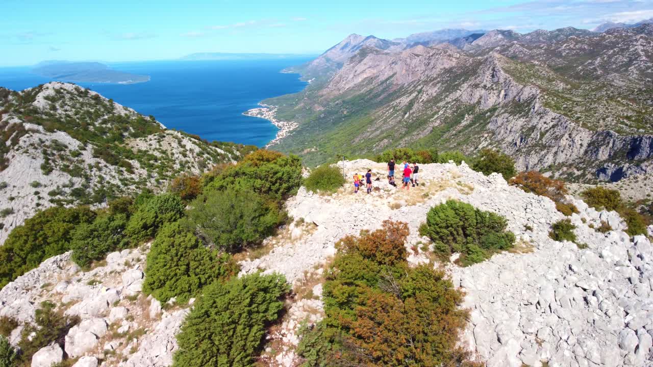 Aerial orbit of hikers navigating trail to peak on Mount St. Ilija, Croatia, rugged terrain and scenic views