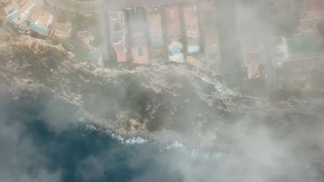 hermosa toma aérea de arriba hacia abajo de una costa con niebla - nubes por todas partes - 4k