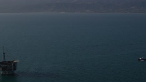 An-vista-aérea-shot-over-a-boat-heading-out-to-oil-derricks-and-platforms-in-the-Santa-Barbara-Channel-California