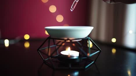 close up of oil lamp with burning candle on wooden table and garland lights on background