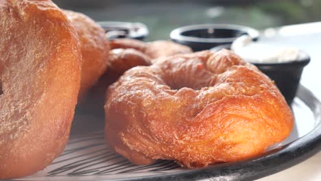 hand picking up a donut from a plate of donuts