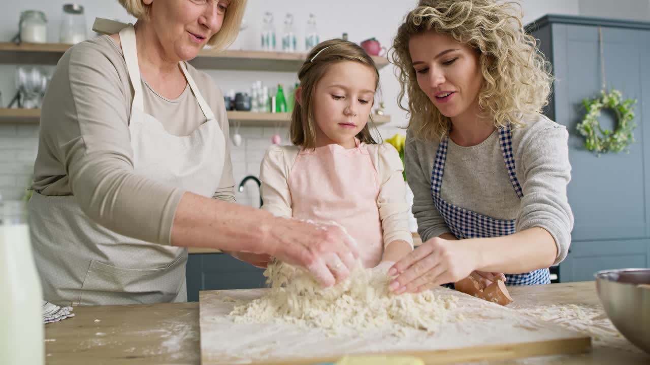 Front view of girl with mom and grandma making dough