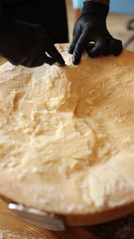 chef cutting a wheel of parmesan cheese