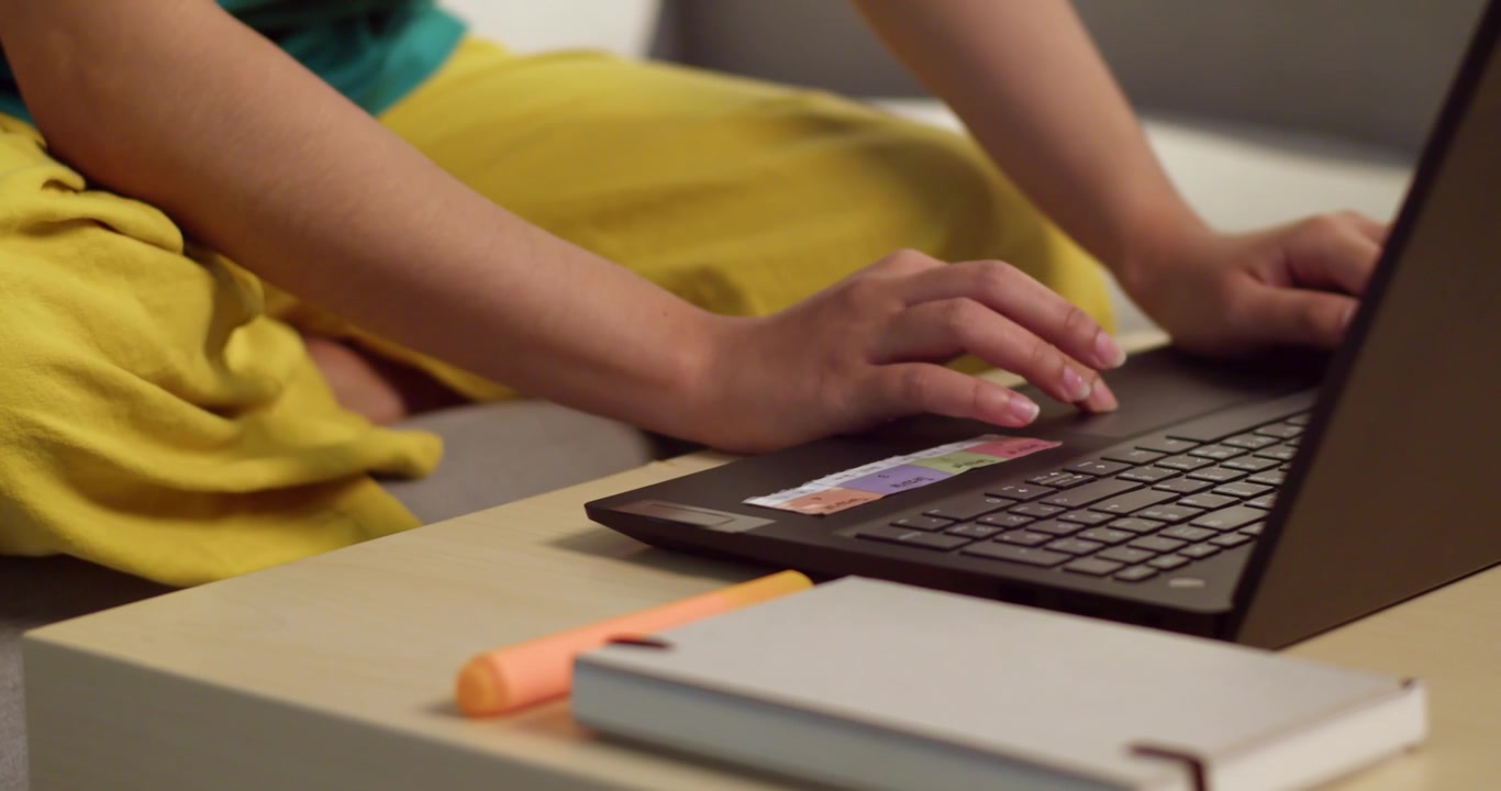 Um close-up de mãos digitando em um laptop em um ambiente aconchegante de escritório em casa.