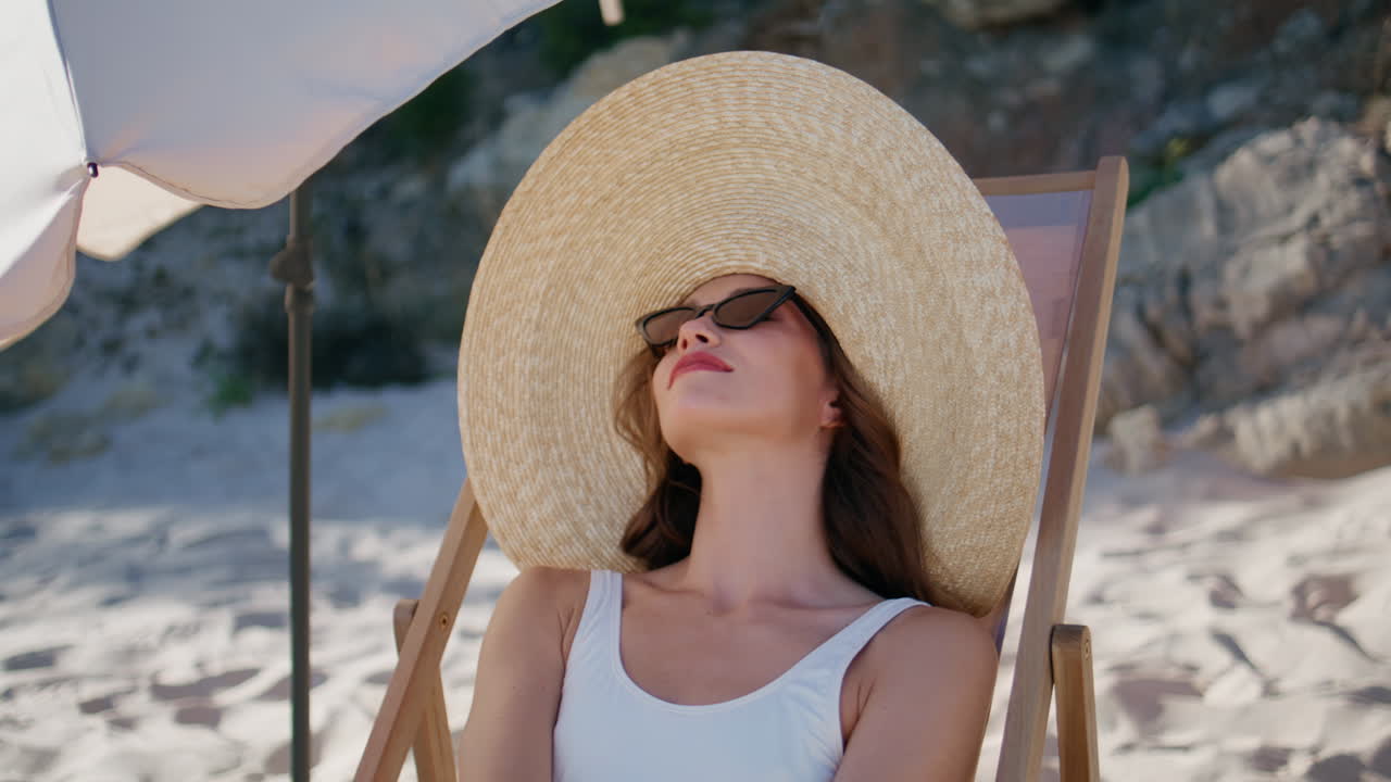 Happy lady enjoying beach relax lying at sun lounger in straw hat closeup