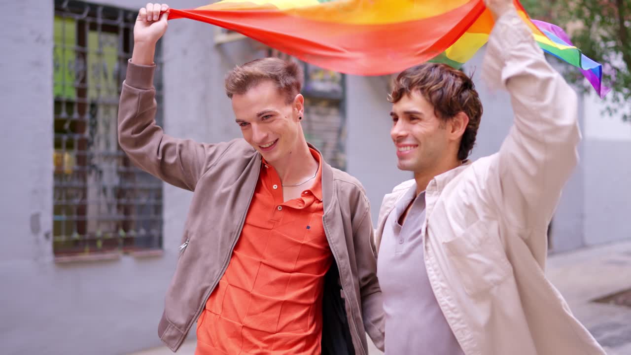 Happy Gay Couple Walking with Rainbow Flag on City Street