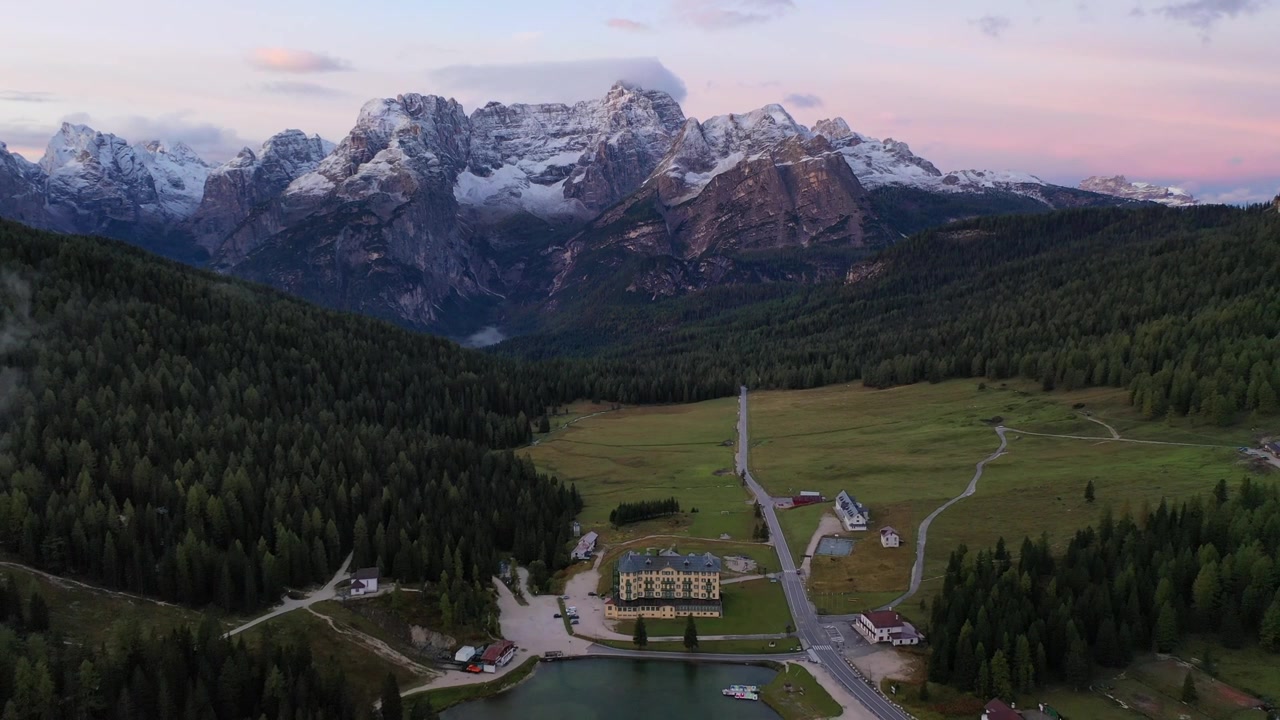 Betagende højvinkel droneoptagelse af den barske Monte Pelmo bjergtop i de italienske Dolomitter. Viser snedækkede klippeformationer, lave dal-skyer og varmt gyldent solnedgangslys.