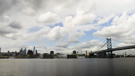 Skyline-Von-Philadelphia-über-Dem-Ruhigen-Delaware-River-Mit-Der-Benjamin-Franklin-Brücke-Mit-Gewitterwolken