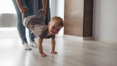 toddler boy crawling on floor at home, playing with mom