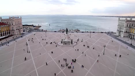 wide view of people walking around in praça do comércio, terreiro do paço, right by the tagus river, in the center of lisbon, portugal