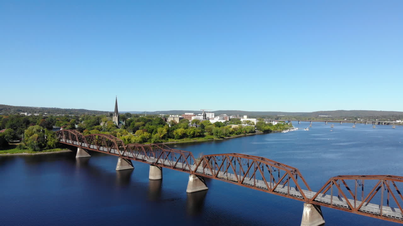 AERIAL: Quickly Moving Backward Away From Downtown Fredericton With A Walking Bridge Being Revealed In Foreground.