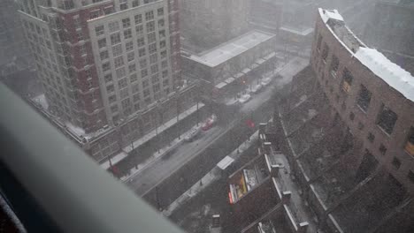 Wide-high-vantage-point-view-of-a-Robson-street-in-city-of-Vancouver-Canada-during-a-white-strong-snow-storm-blizzard-blowing-sideways-with-people-walking-the-streets