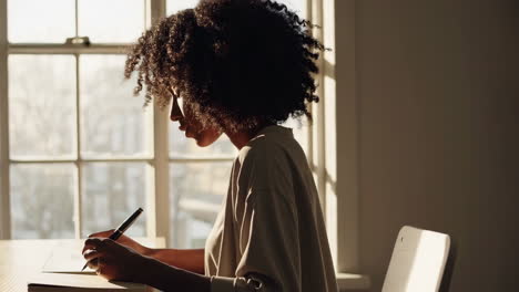 woman writing and studying by a sunny window