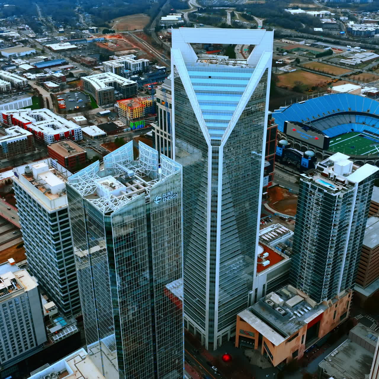 Flying around the magnificent skyscrapers with mirror windows in the downtown of Charlotte, North Carolina, USA. City scenery on cloudy daytime.