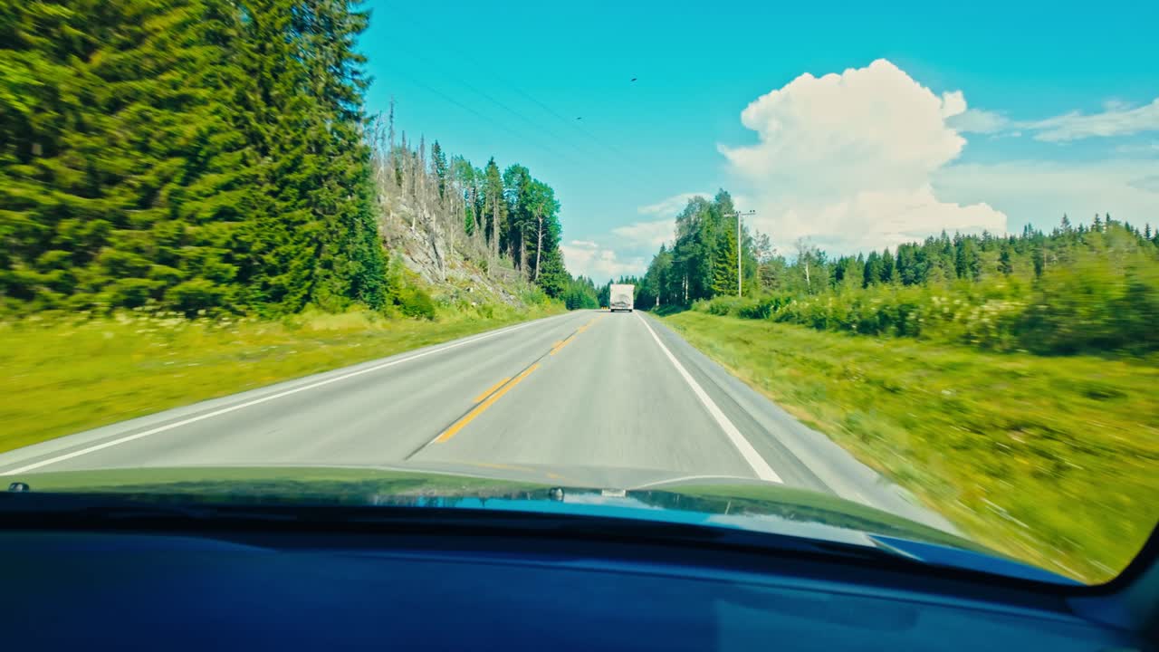 Fahrt nach Norden auf der E6: Die Straße zieht sich durch eine sonnenbeschienene Waldlandschaft in Fosen, Trøndelag, Norwegen – POV-Aufnahme