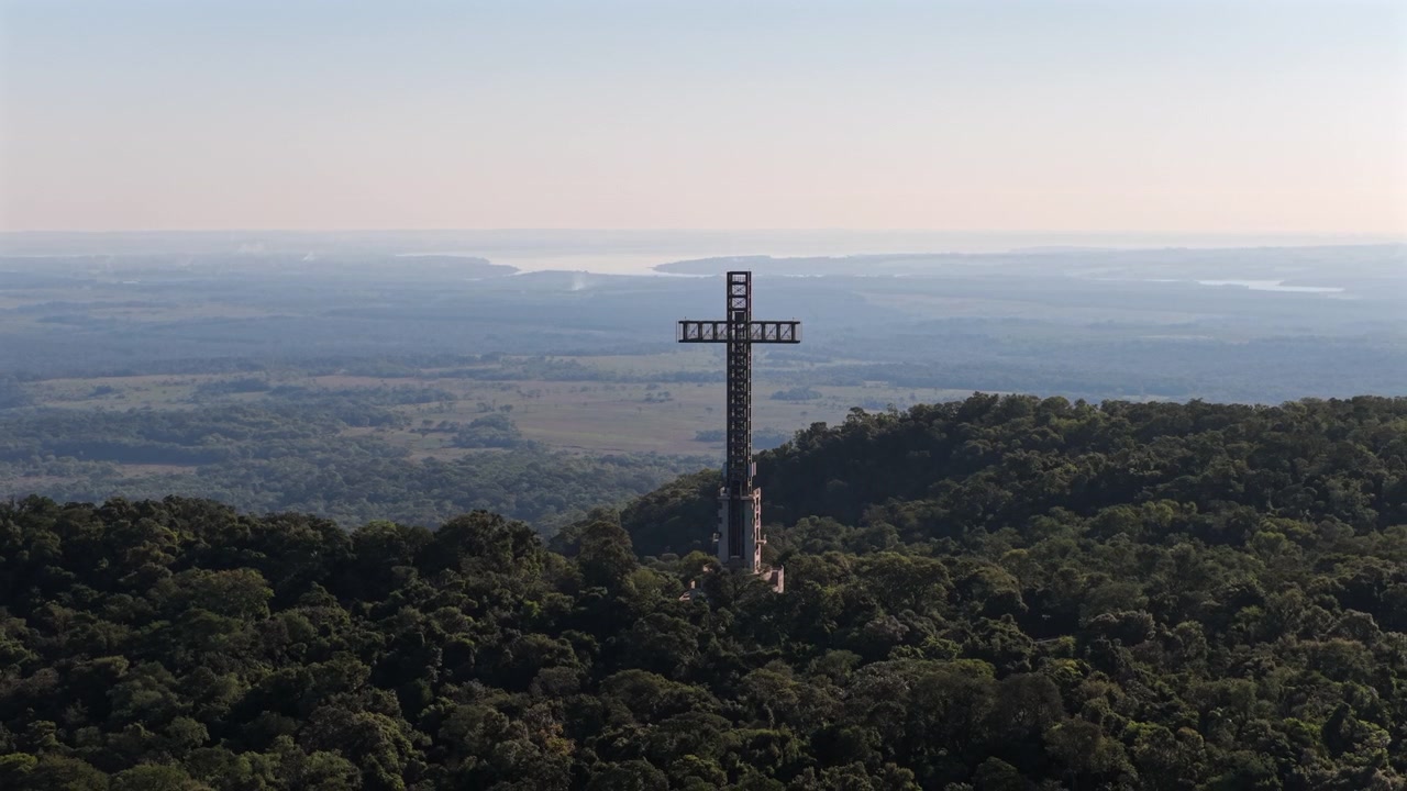 Vista drone di un grande monumento a croce sopra colline boscose e una lontana valle fluviale