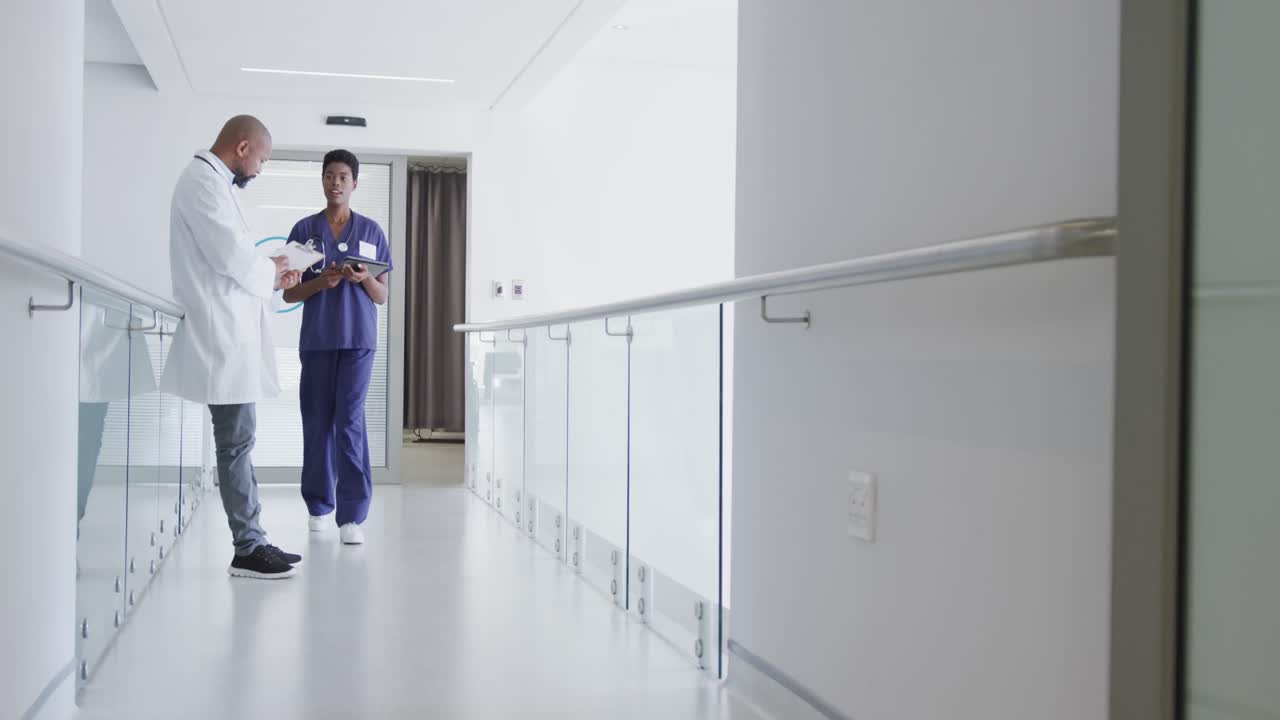 Médicos e médicas afro-americanos segurando prancheta e tablet, conversando no hospital.